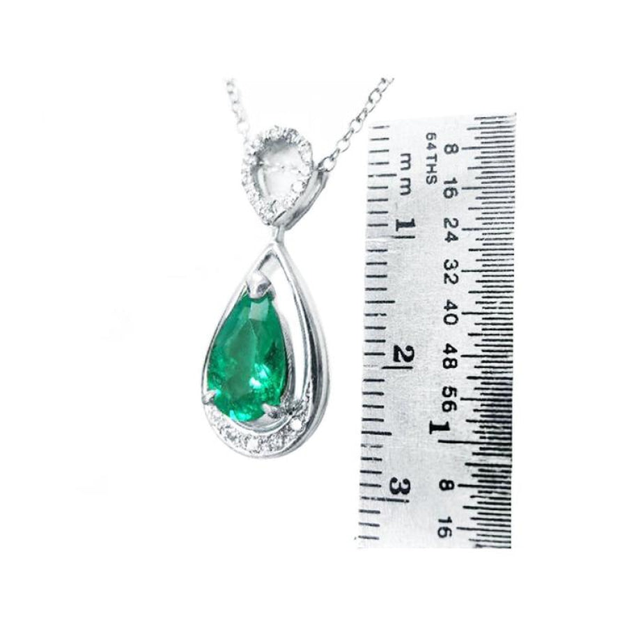 1.35 ct natural pear-shaped emerald pendant necklace with diamond bail in 14K white gold, shown with ruler.