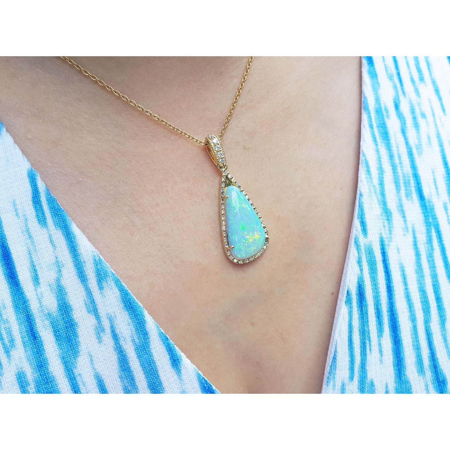 Opal pendant necklace on a person wearing a blue and white striped garment.