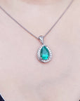 Emerald green teardrop pendant on a white gold chain against a neutral background