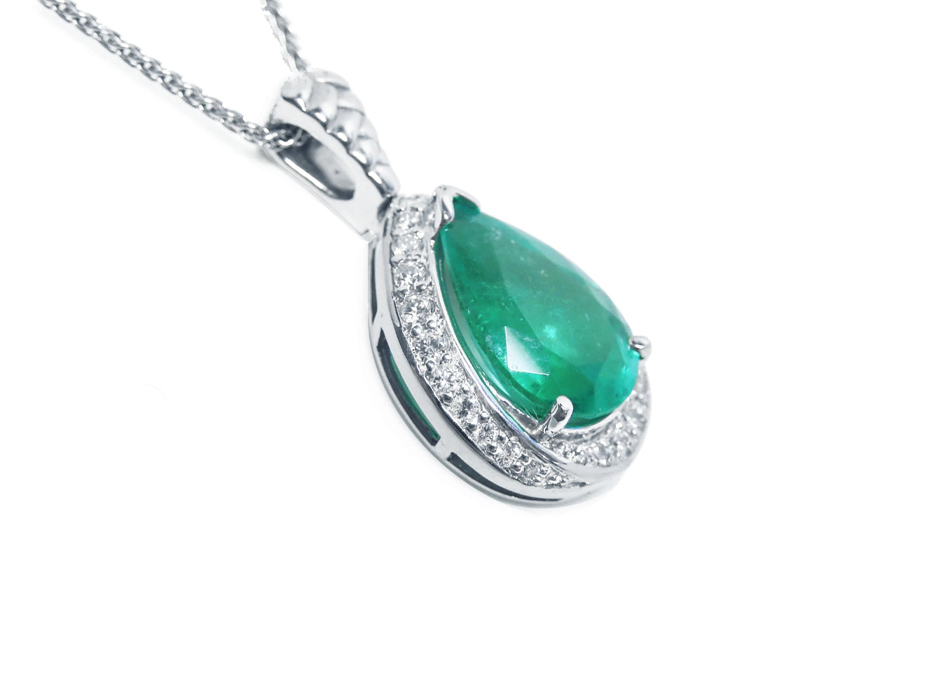 Silver pendant with a green teardrop emerald on a right-side profile visible