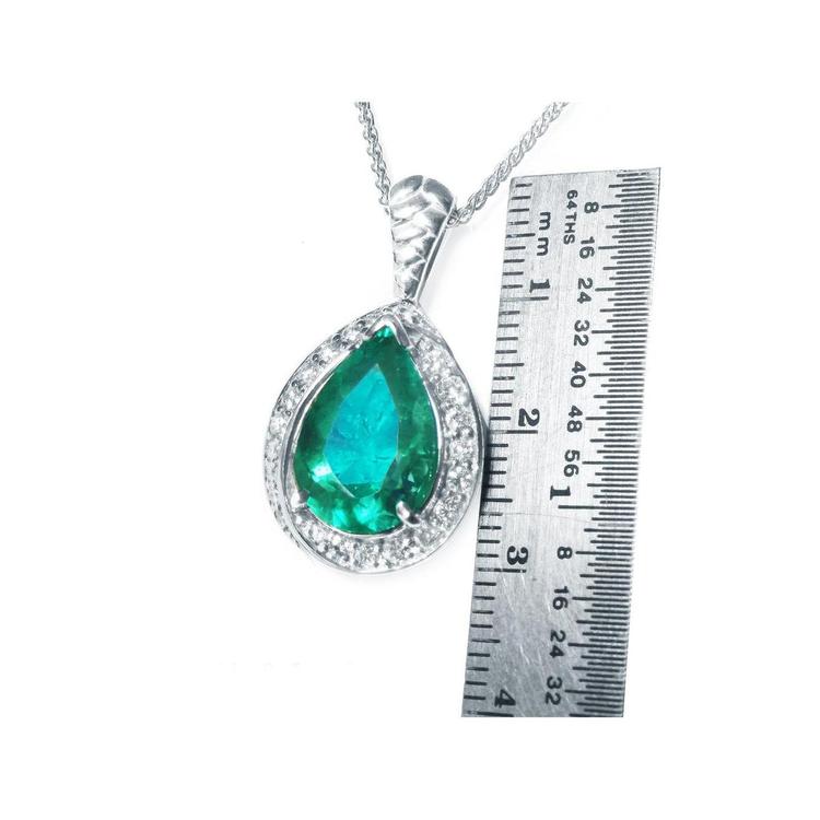 Pear-shaped Colombian emerald pendant with diamond halo in 14K white gold, shown next to a ruler.