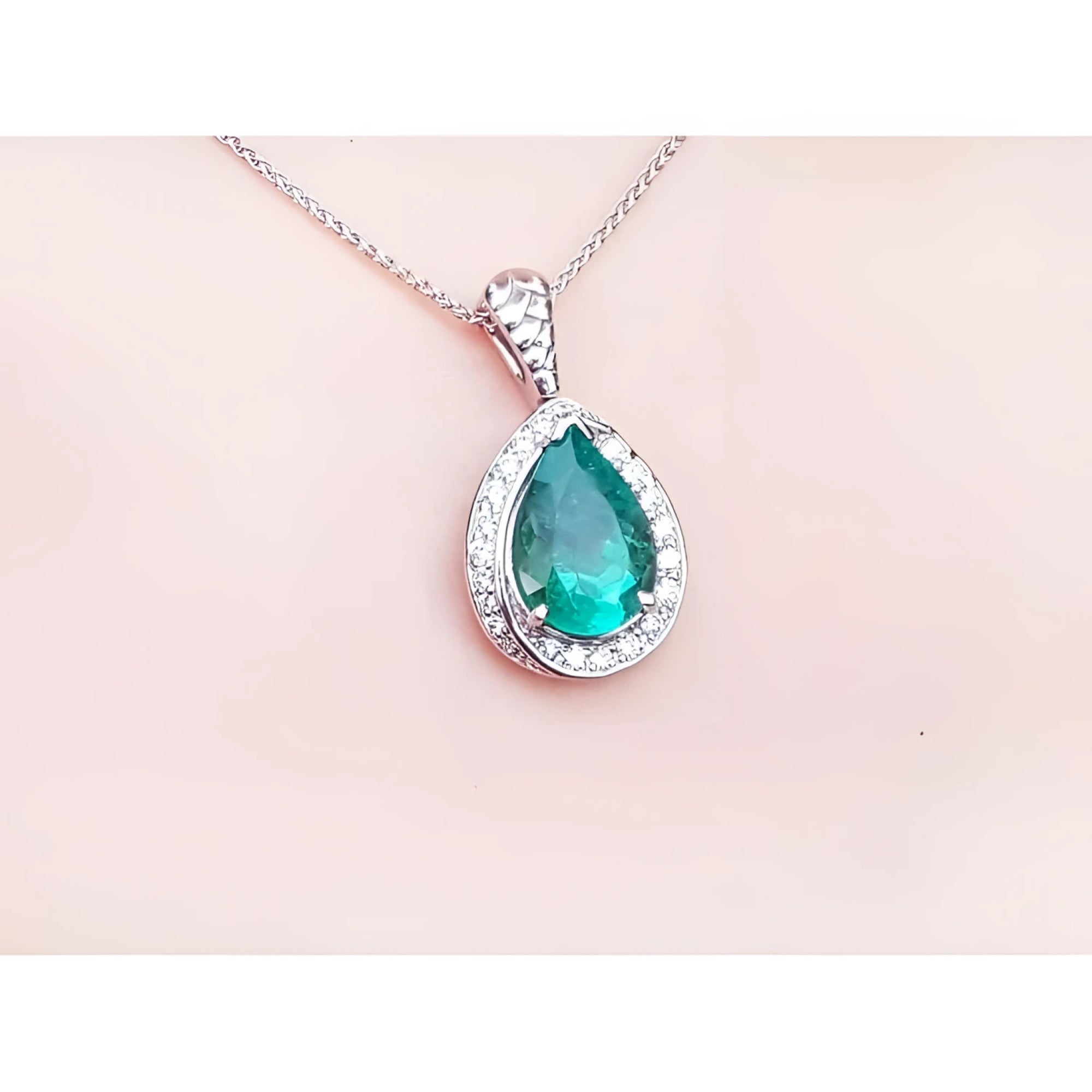 Pear-shaped natural emerald pendant with diamond halo, set in 14K white gold on a delicate chain.