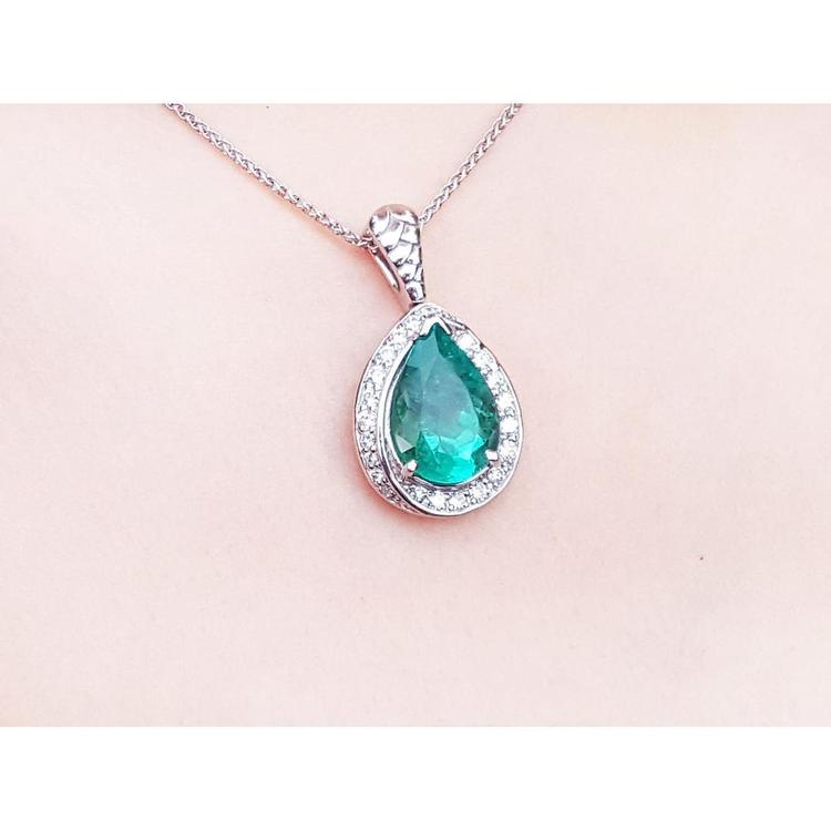 Pear-shaped natural emerald pendant with diamond halo, set in 14K white gold on a delicate chain.