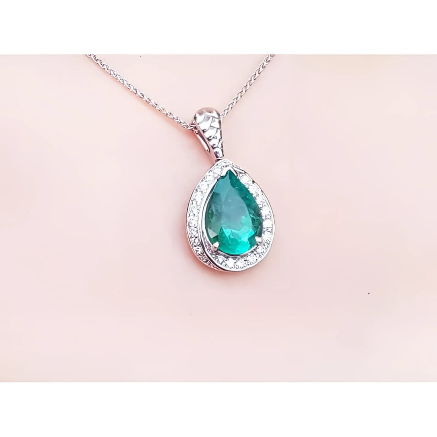 Pear-shaped natural emerald pendant with diamond halo, set in 14K white gold on a delicate chain.