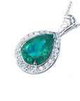 Teardrop-shaped emerald pendant with diamond accents on a left side position topside view