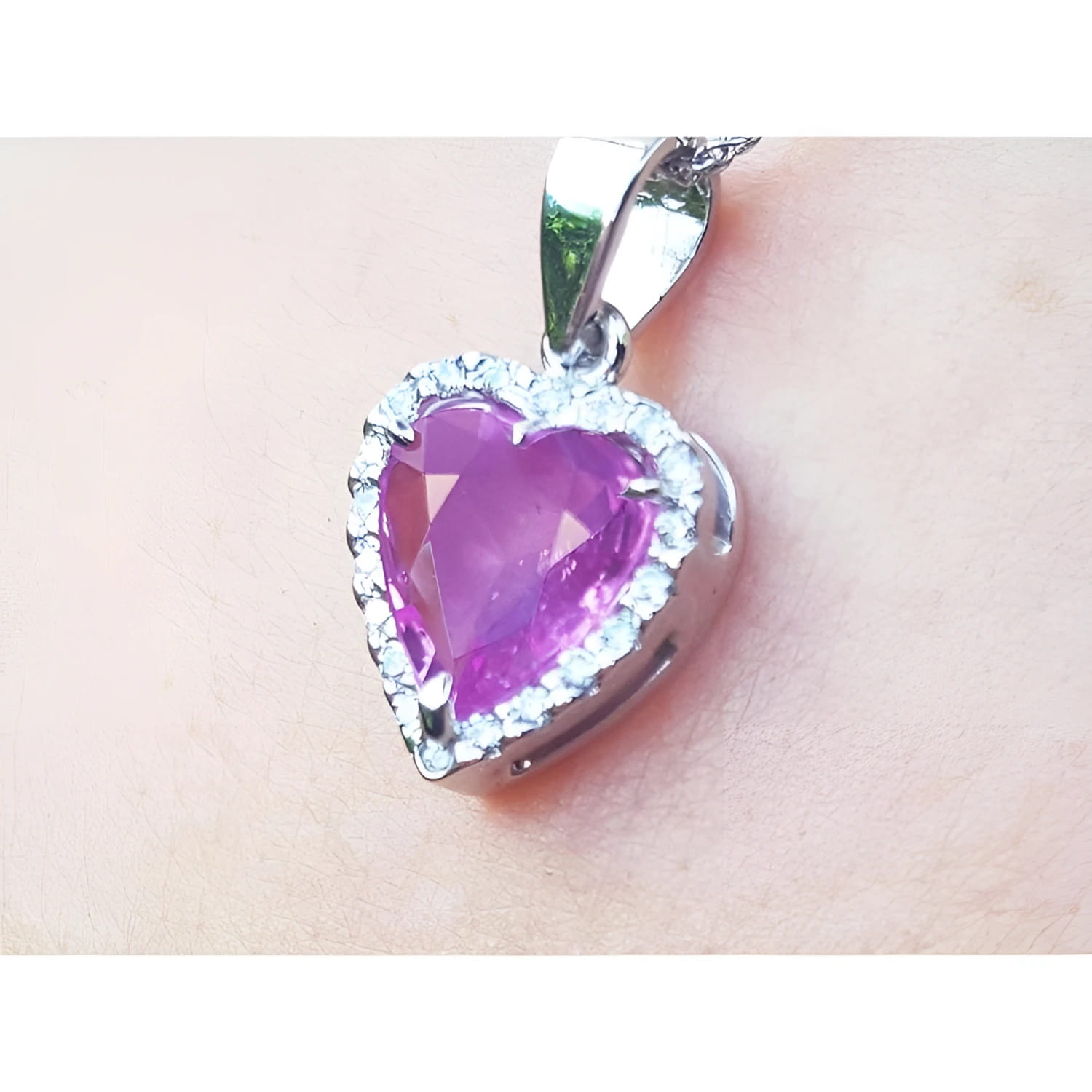 Heart-shaped natural sapphire pendant halo diamond in white gold close-up view on woman's neck