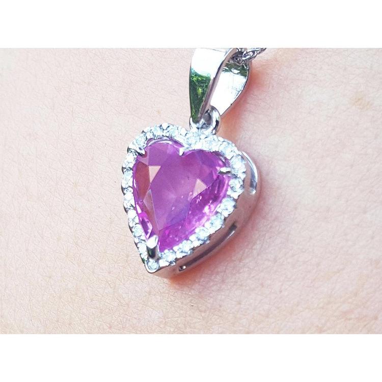 Heart-shaped natural sapphire pendant halo diamond in white gold close-up view on woman's neck