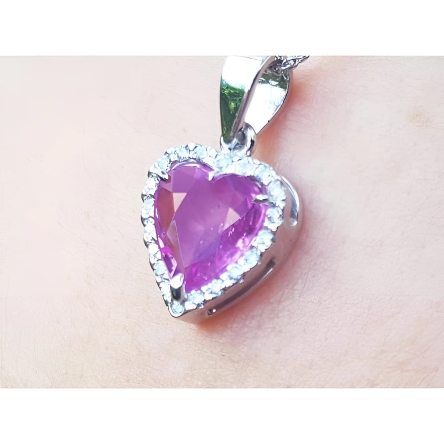 Heart-shaped natural sapphire pendant halo diamond in white gold close-up view on woman's neck