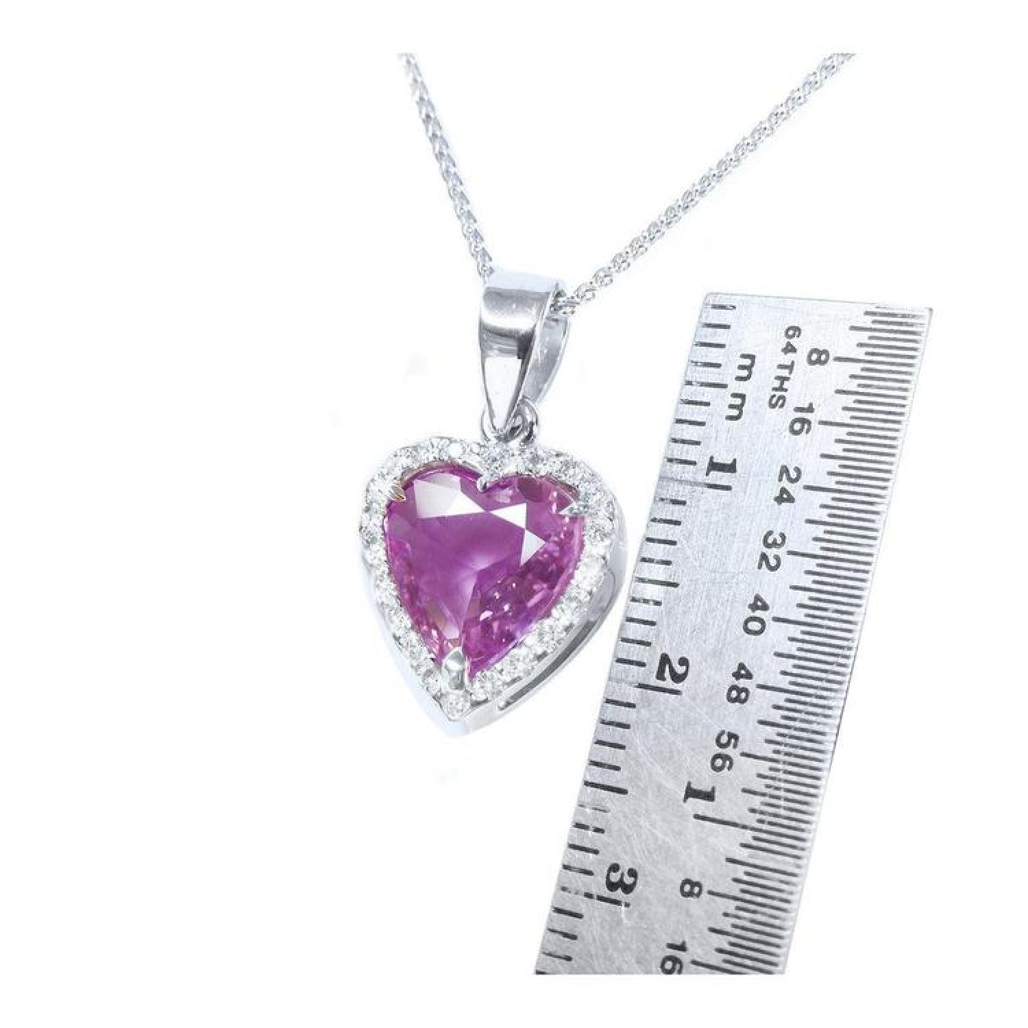 Heart-cut natural pink sapphire pendant with diamond halo on an 18K white gold chain, next to a ruler.
