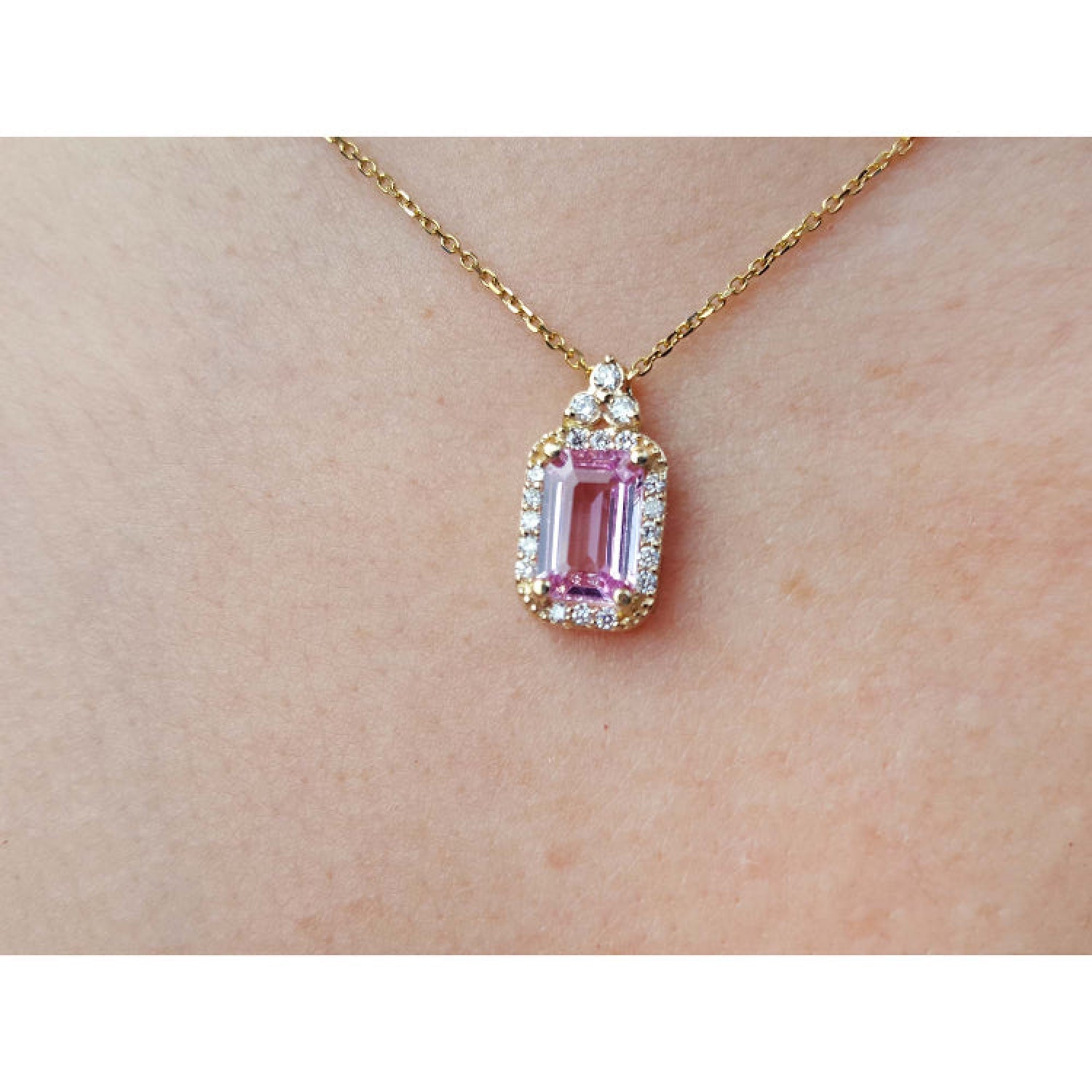 Natural pink sapphire and diamonds pendant necklace on a person's neck.