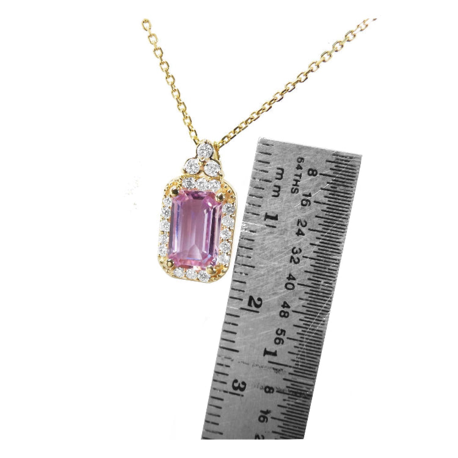 Pink sapphire necklace with gold chain next to a ruler for scale in 14k gold.