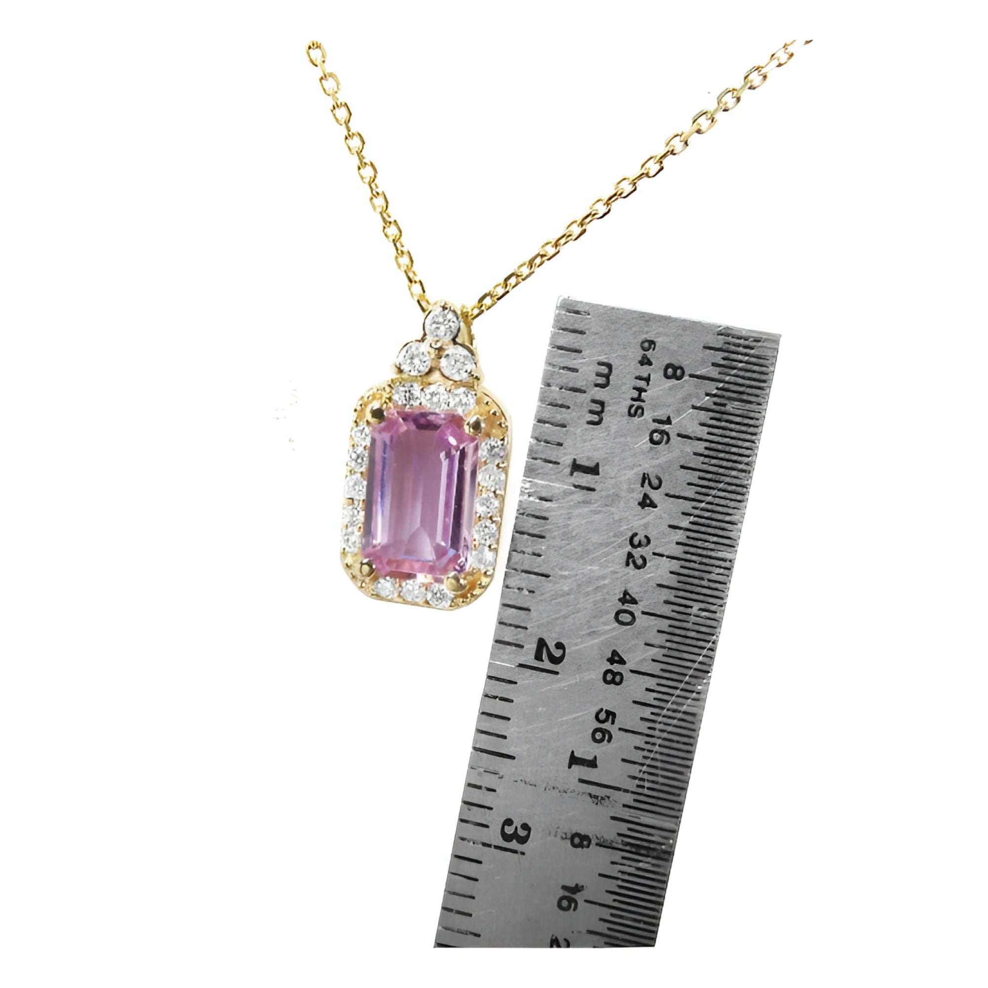 Pink sapphire necklace with gold chain next to a ruler for scale in 14k gold.