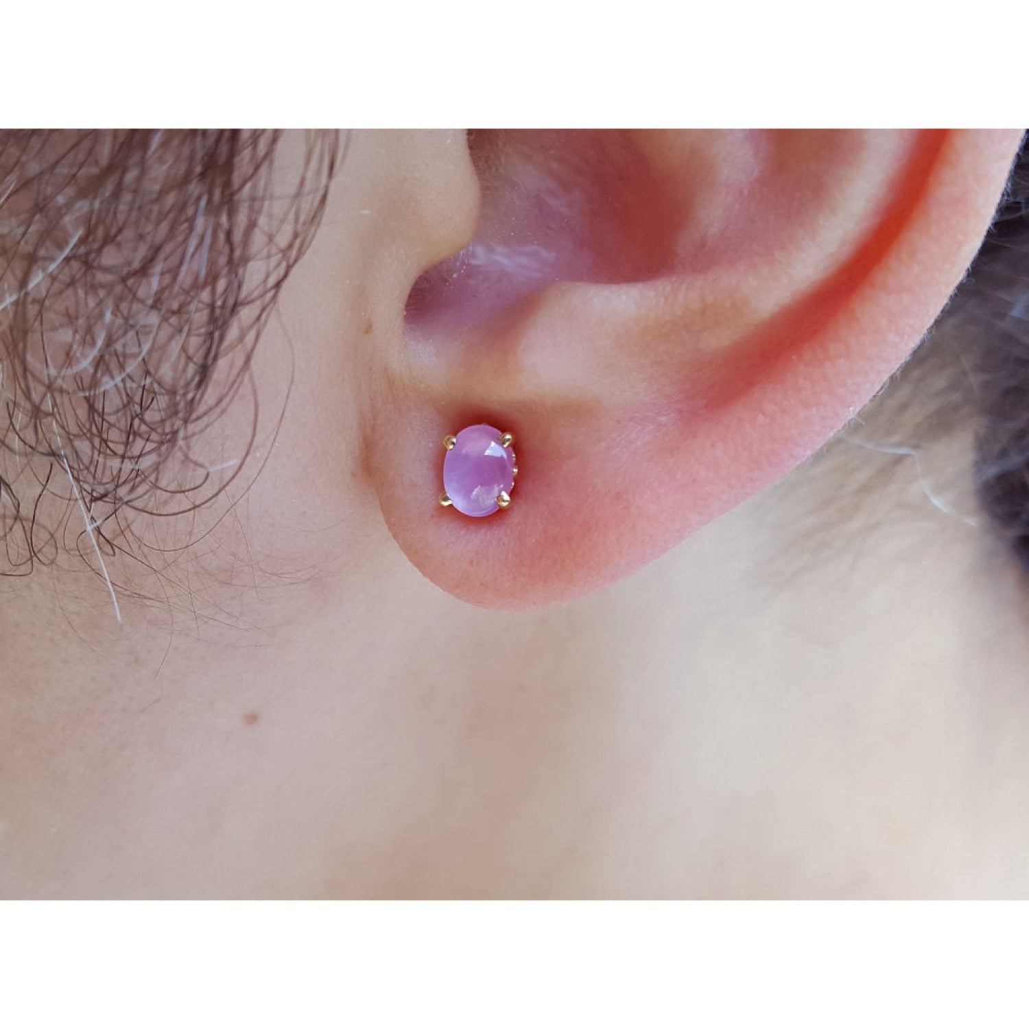 Close-up of an ear wearing a pink star sapphire earring.