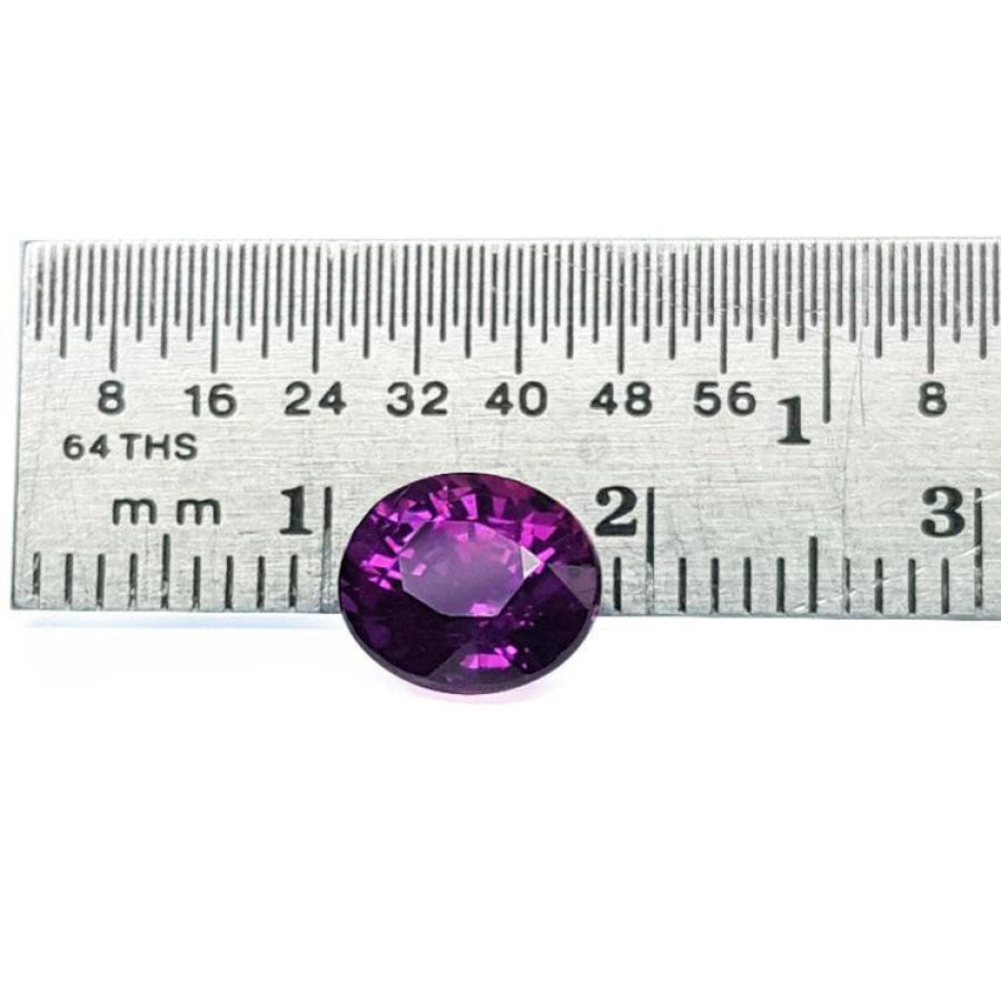 2.59 ct natural intense vivid purple-pink oval cut sapphire gemstone next to a ruler.