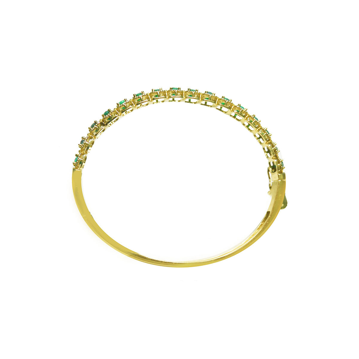 The lateral side profile view of a gold bangle bracelet with emeralds on a white background.