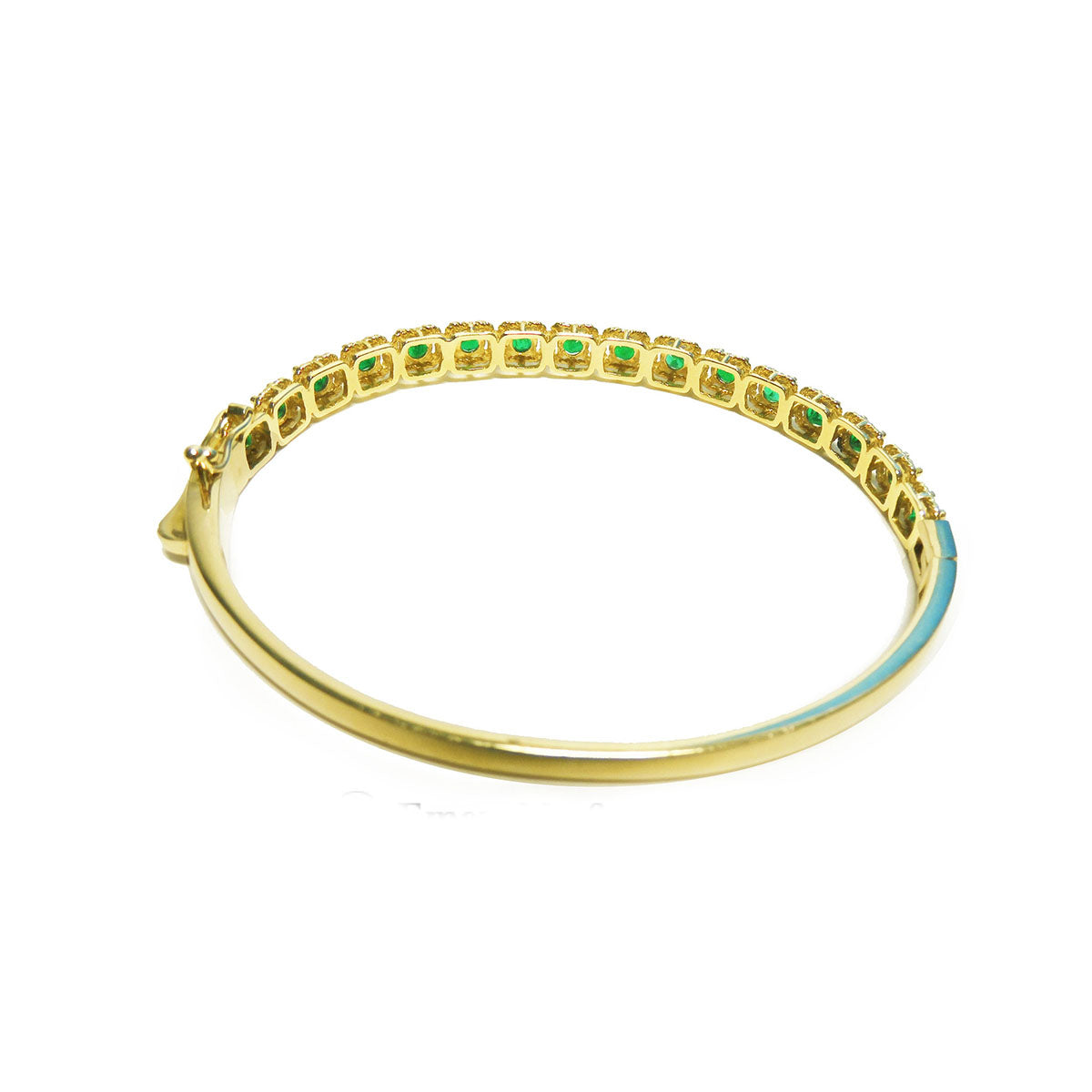 A yellow gold bangle bracelet with round cut emeralds on a underside view position.
