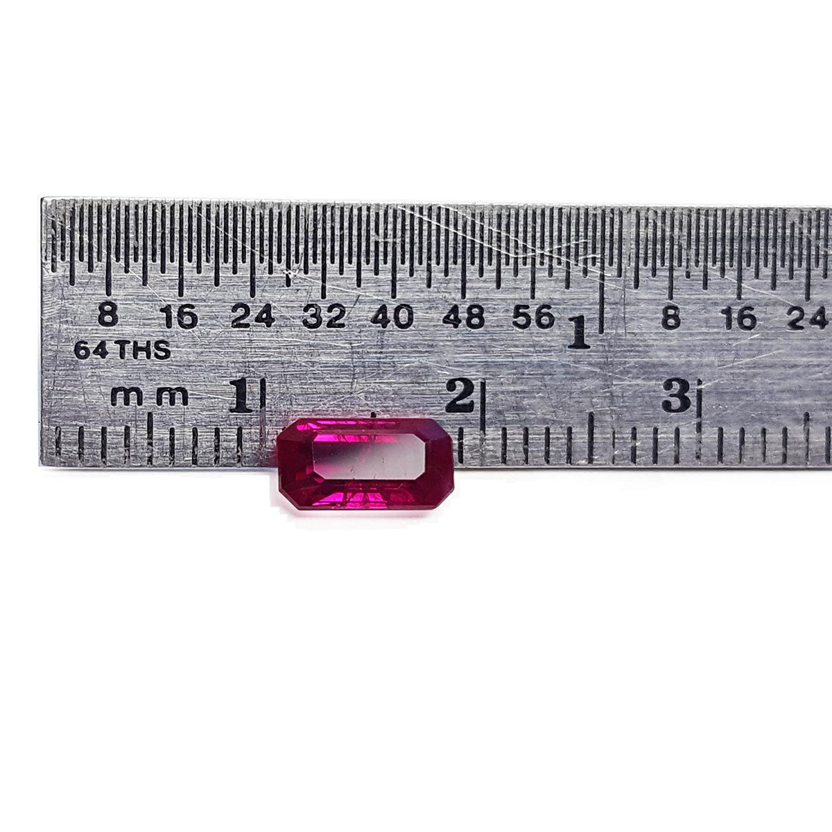 Loose ruby natural gemstone emerald-cut on a ruler for scale