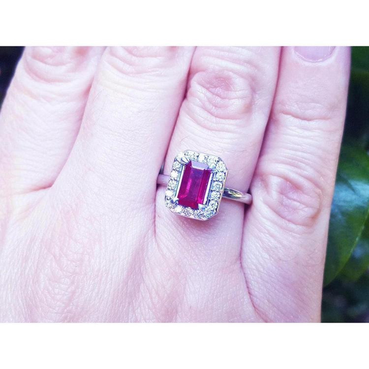 Women's 14K white gold ring with an emerald-cut deep red ruby and diamond halo.
