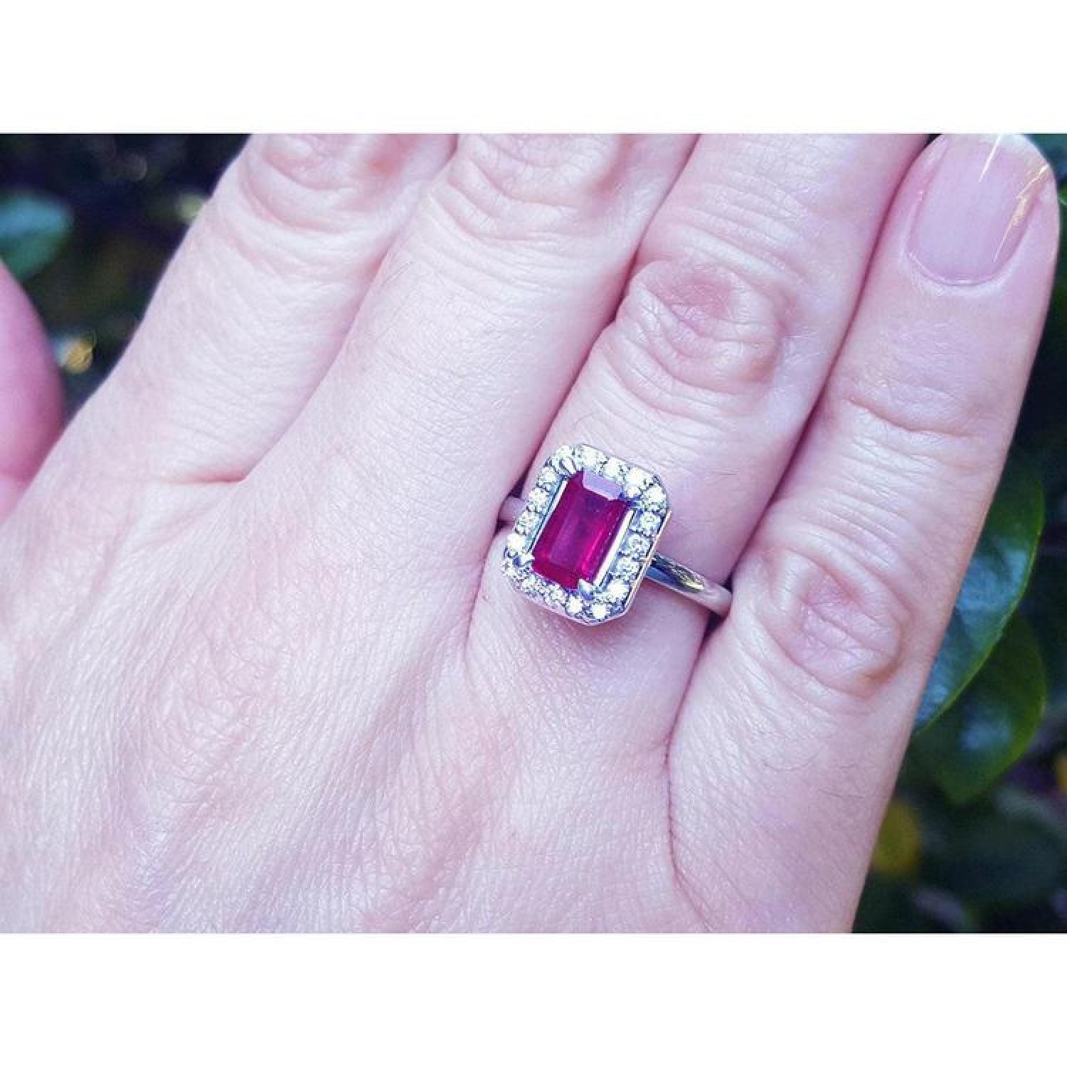 Women's 14K white gold ring with an emerald-cut deep red ruby and a halo of sparkling diamonds.