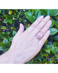 Hand wearing a natural ruby ring for women, gemstone against a green leafy background