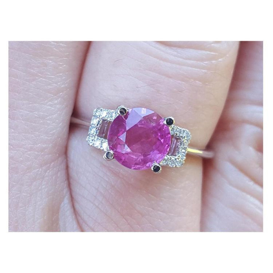 Round cut pinkish-red ruby ring with accented diamonds in 14k white gold.