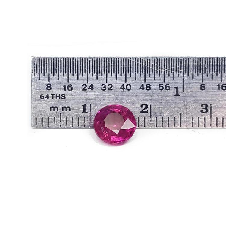 1.64 carat natural round cut ruby with vibrant medium red hue, shown next to a ruler for scale.
