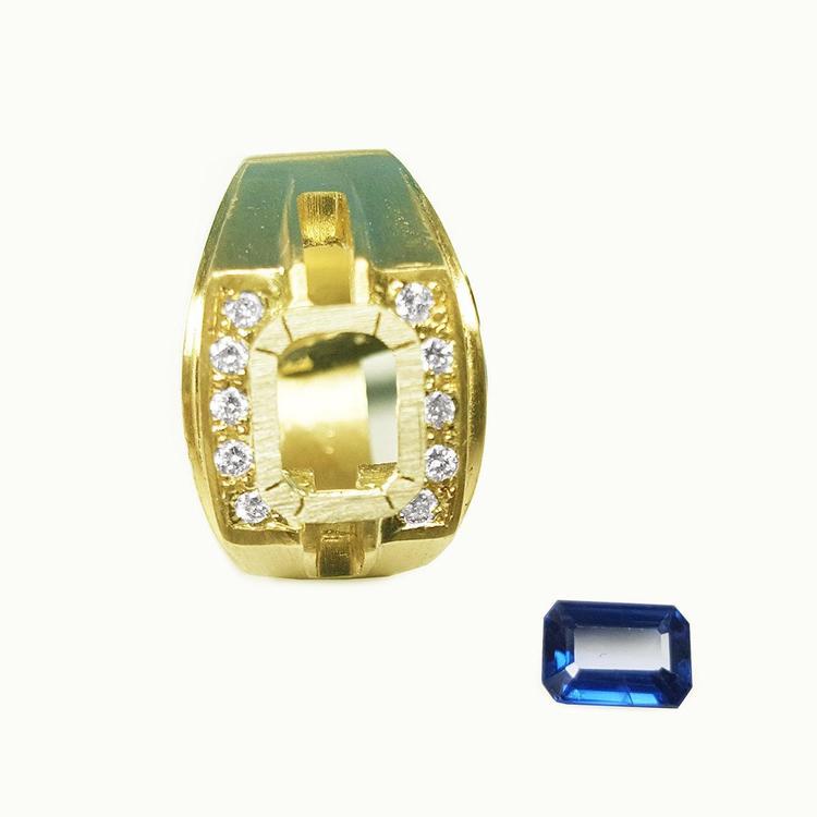 18K yellow gold men's ring setting with diamond accents, next to a loose rectangular blue sapphire.