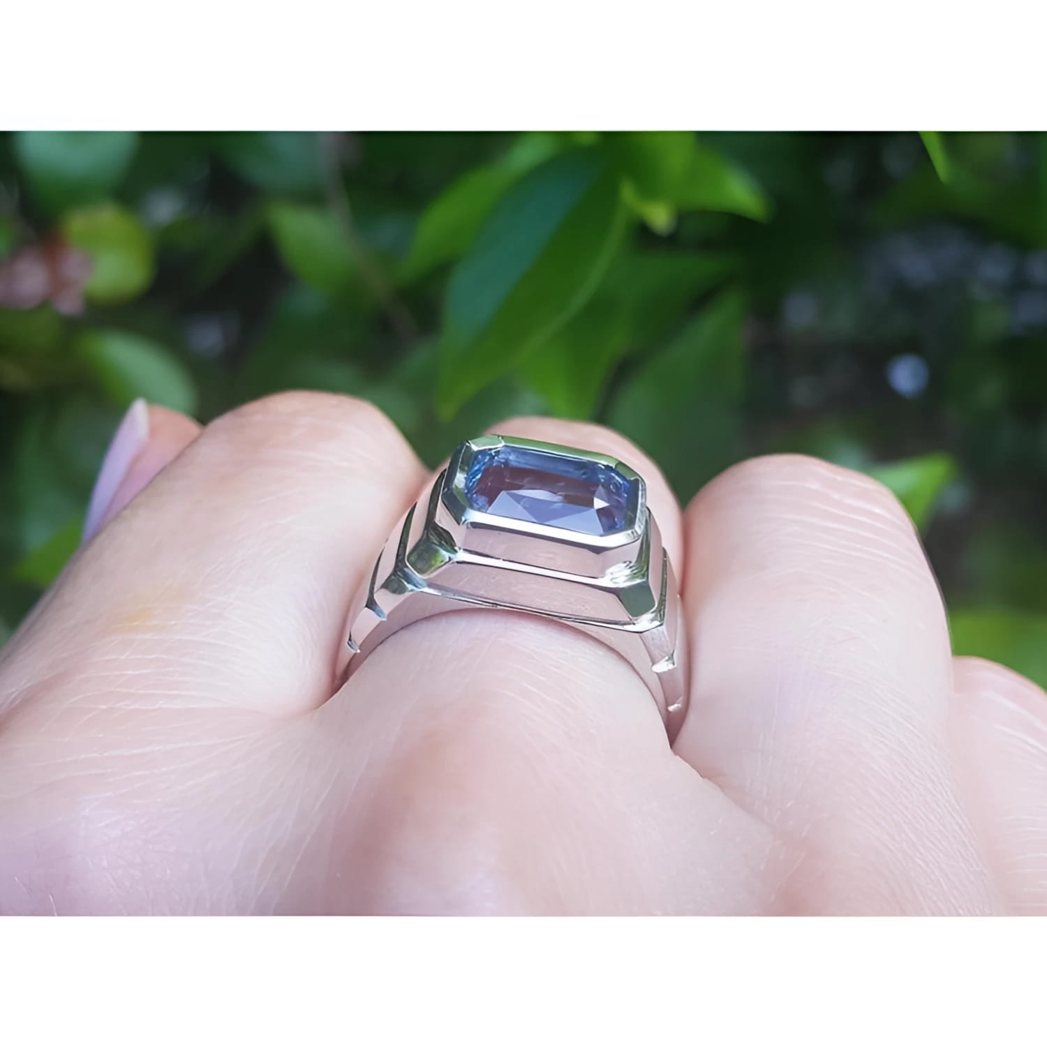 Men's 18K white gold ring with a bezel-set, emerald-cut vivid blue sapphire.
