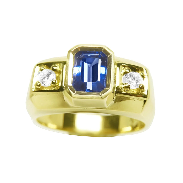 Men’s natural sapphire ring featuring an emerald-cut vibrant medium blue stone in a bezel setting, accented by side round-cut diamonds, crafted in 14K yellow gold.