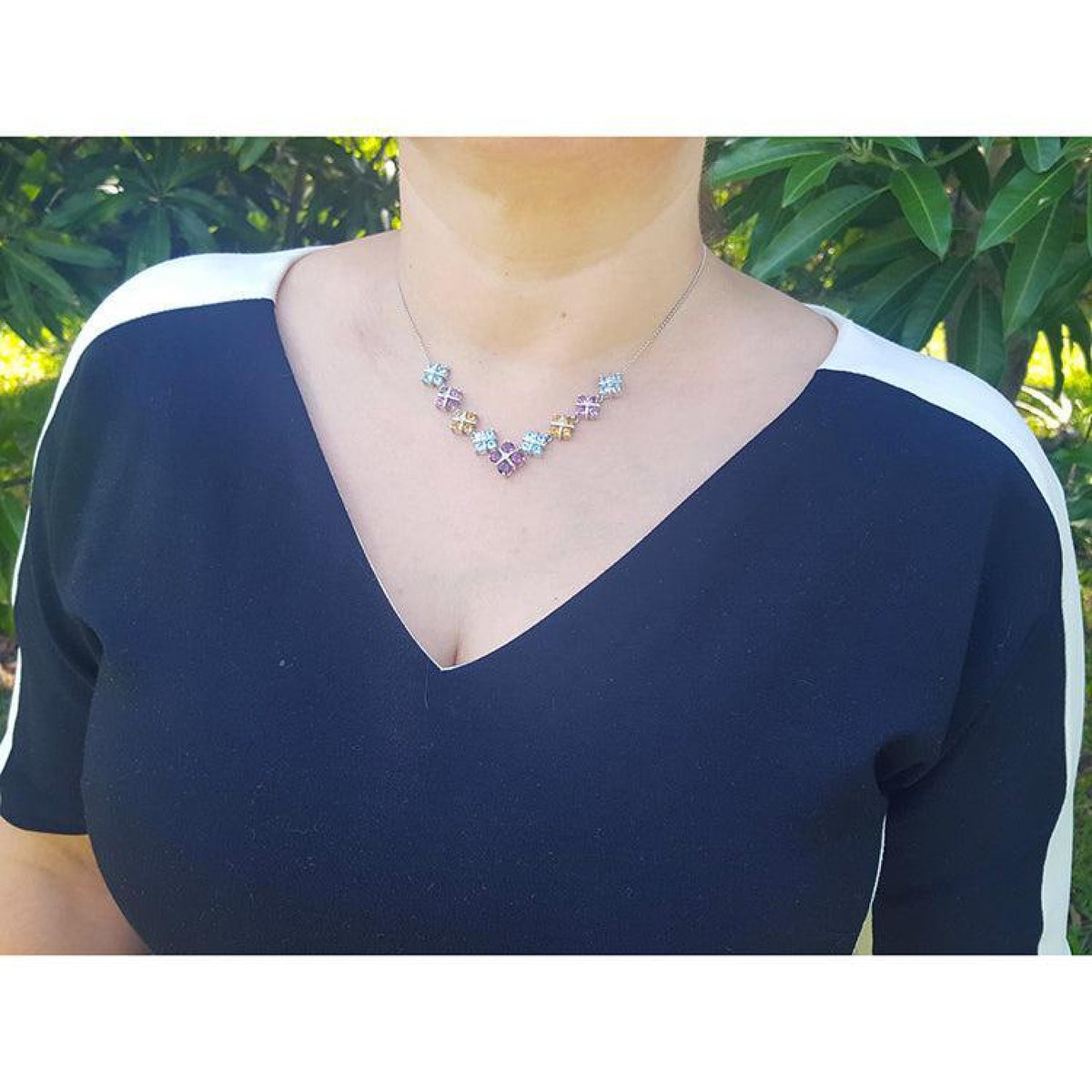 Woman wearing an 18K white gold necklace with tri-colored topaz X-cluster links.