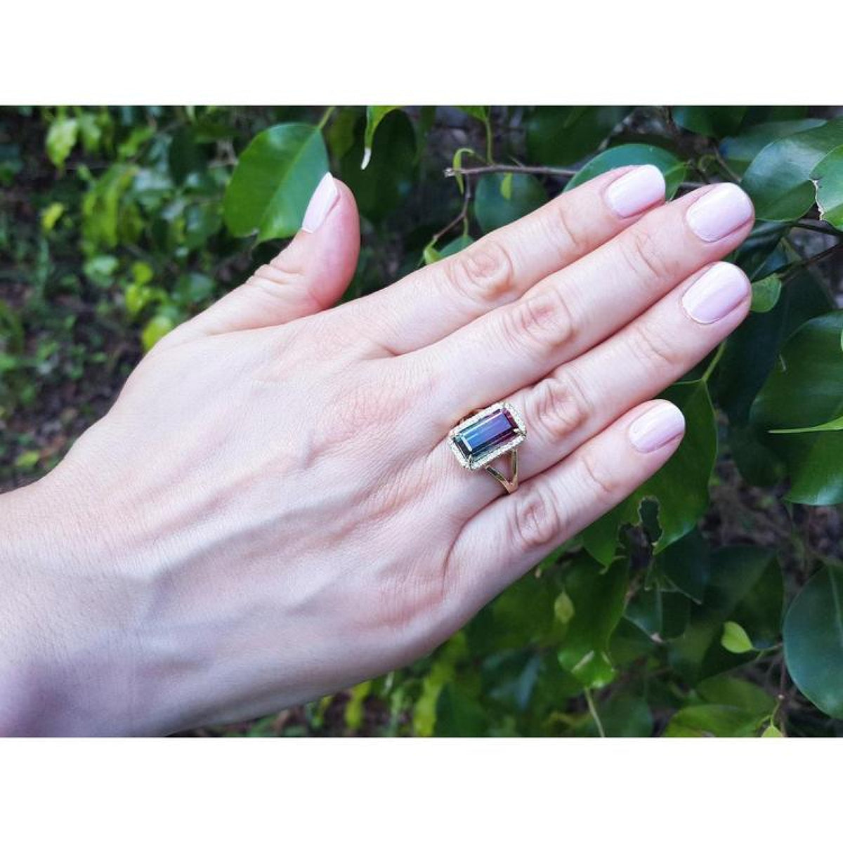 Woman's hand wearing a 14K gold ring with a rectangular 5.60 ct. green and pink watermelon tourmaline.