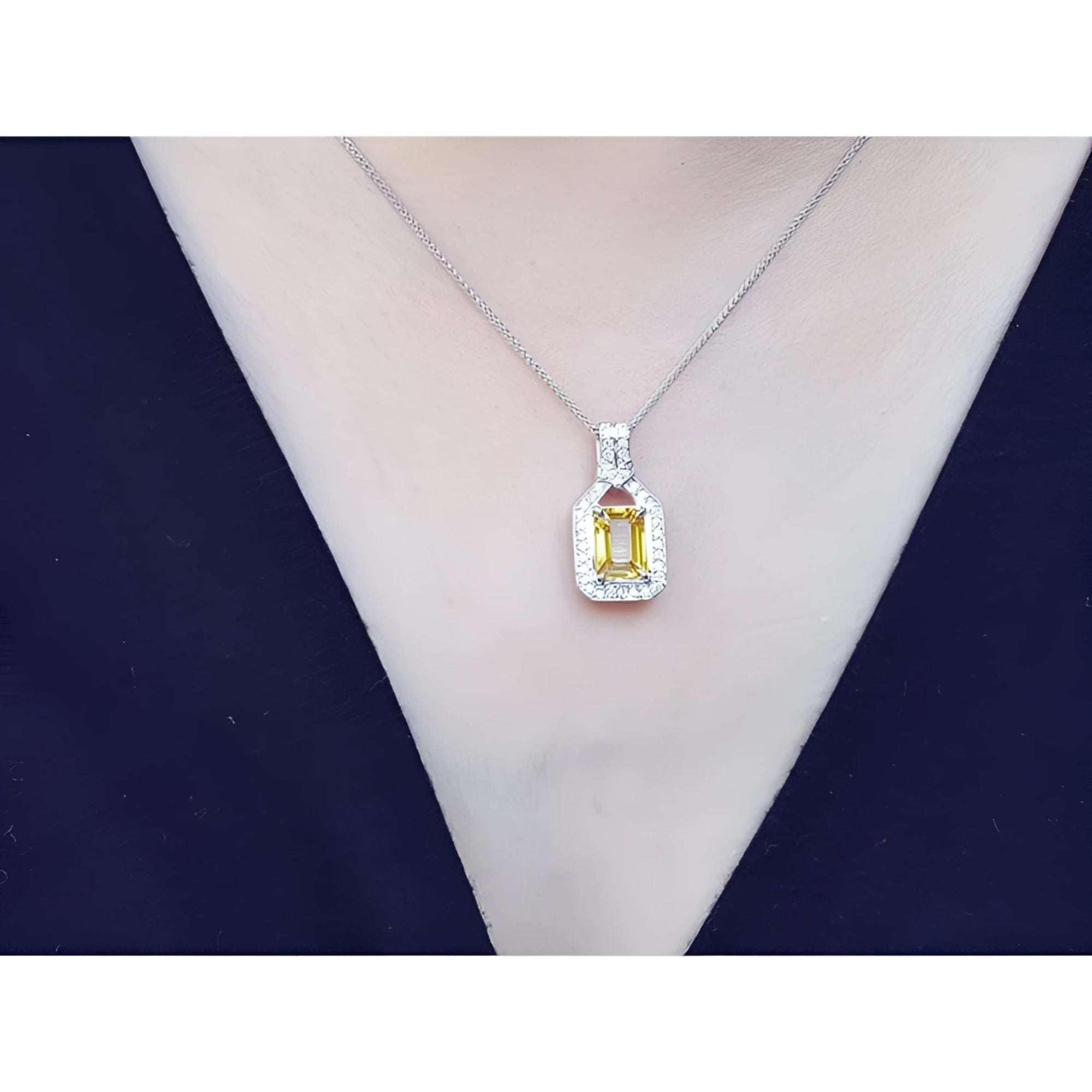 Emerald cut yellow sapphire halo diamond pendant on an 18K white gold chain, worn on a woman.