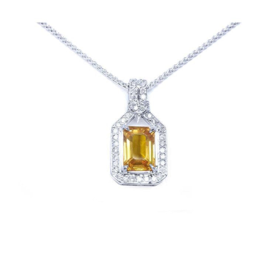 Emerald cut yellow sapphire pendant with halo diamonds on an 18K white gold chain.
