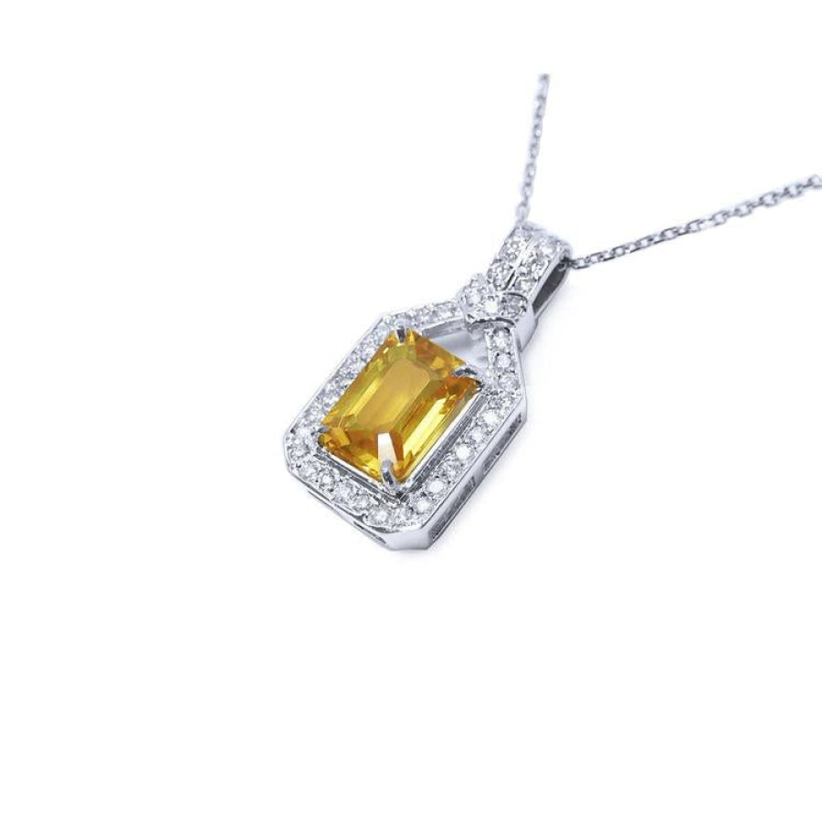 Emerald cut yellow sapphire pendant with halo diamonds on an 18K white gold chain.
