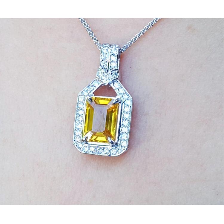 Hanging on a woman's neck a natural yellow sapphire pendant necklace halo diamond 18k white gold