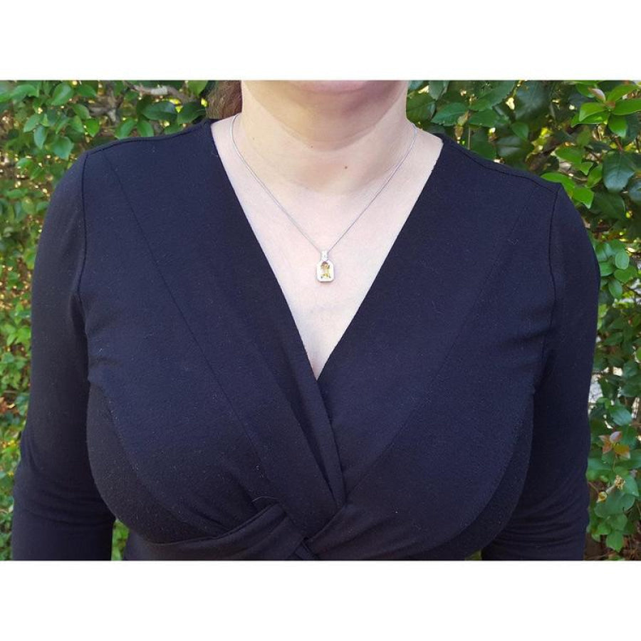 Woman wearing a 2.42 ct. emerald-cut yellow sapphire and diamond halo pendant on an 18K white gold chain.