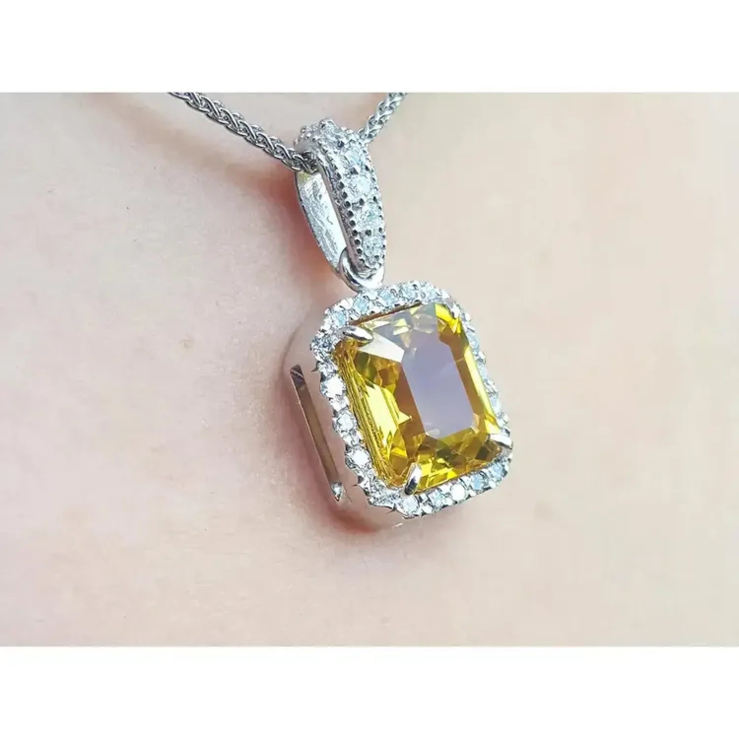 6.01 ct. emerald cut natural yellow sapphire pendant with diamond halo in 18K white gold.