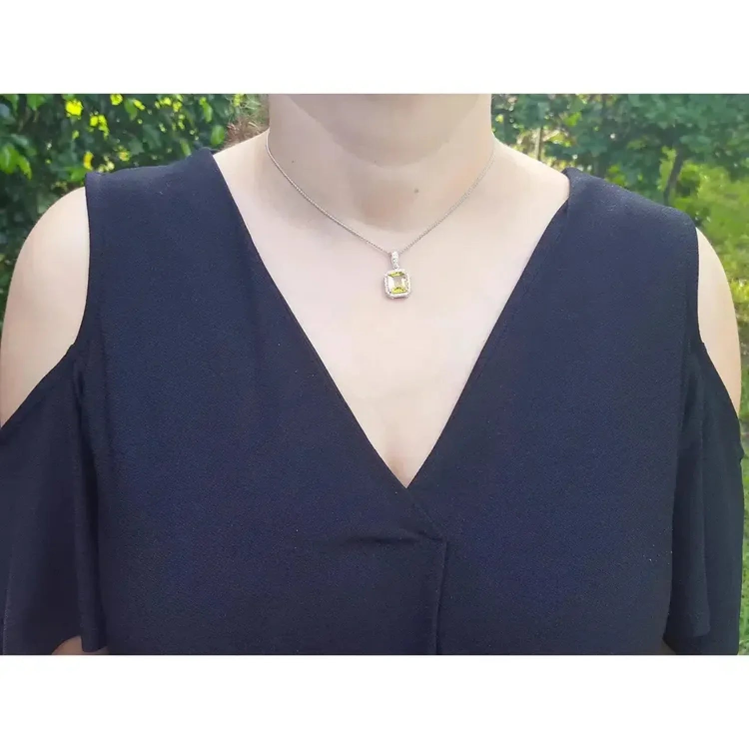 Emerald cut 6.01 ct. natural yellow sapphire pendant with halo diamonds in 18K white gold, worn on a model.