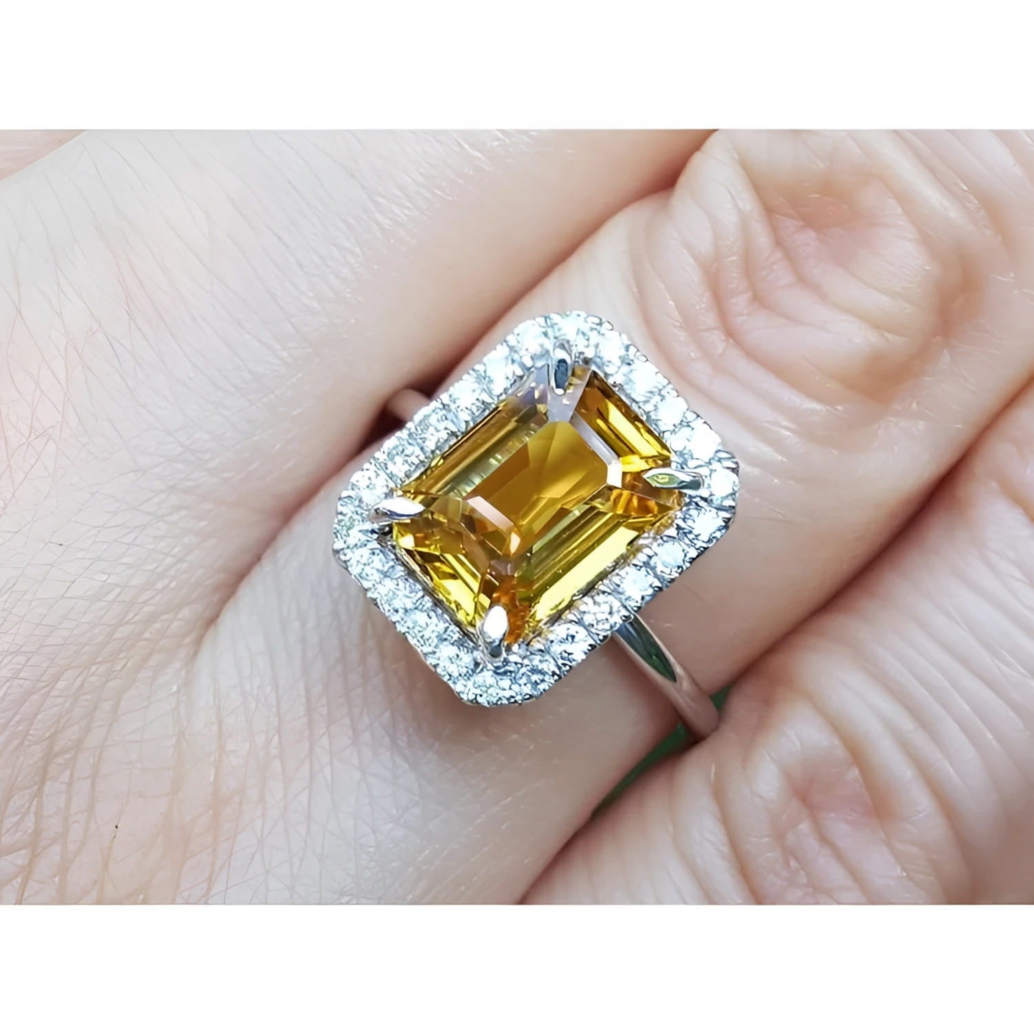14k white gold Ring with a yellow natural sapphire emerald cut and diamond accents on a finger.
