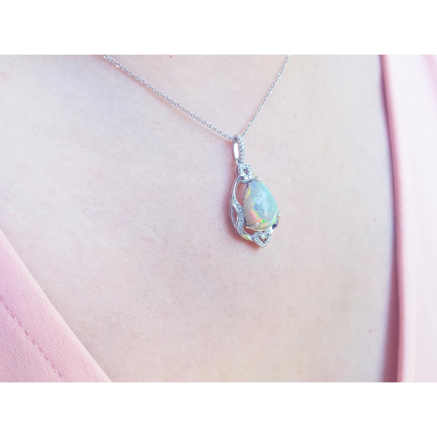 Opal pendant necklace on a pink fabric background.