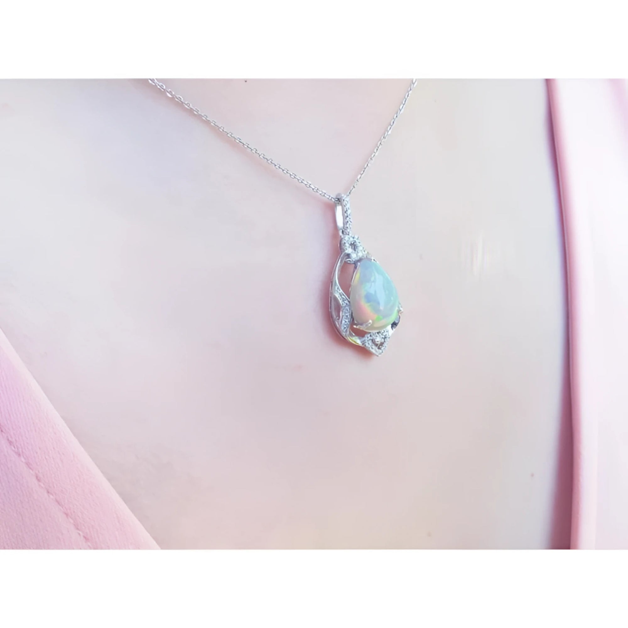 Pear-shaped rainbow Welo Ethiopian opal pendant in sterling silver with cubic zirconia accents on a chain.