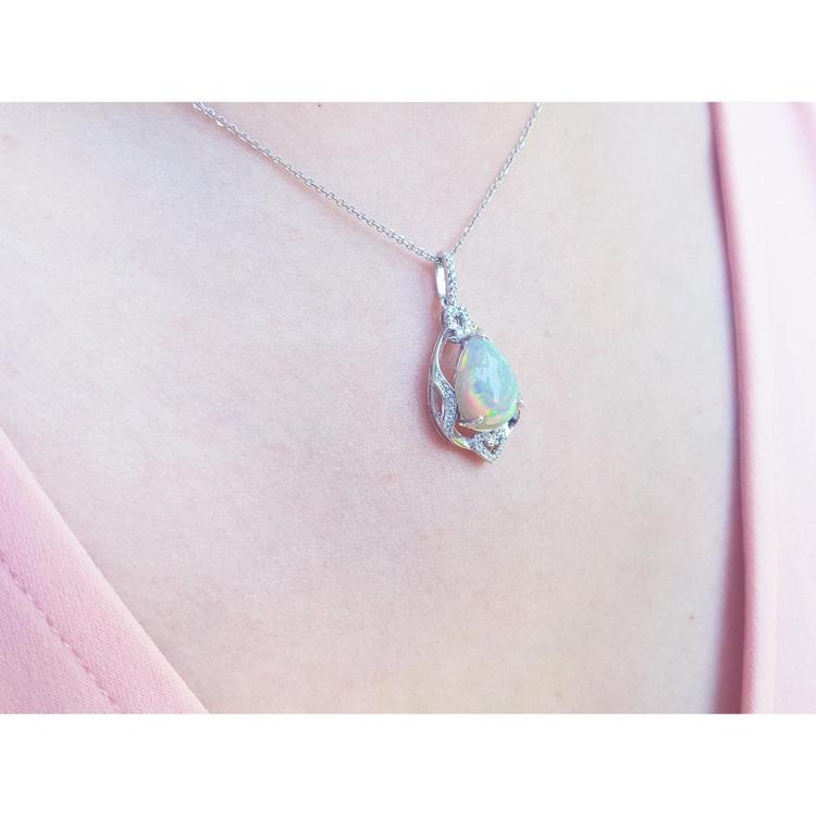 Pear-shaped rainbow Welo Ethiopian opal pendant in sterling silver with cubic zirconia accents on a chain.