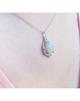 Opal pendant necklace on a pink fabric background.