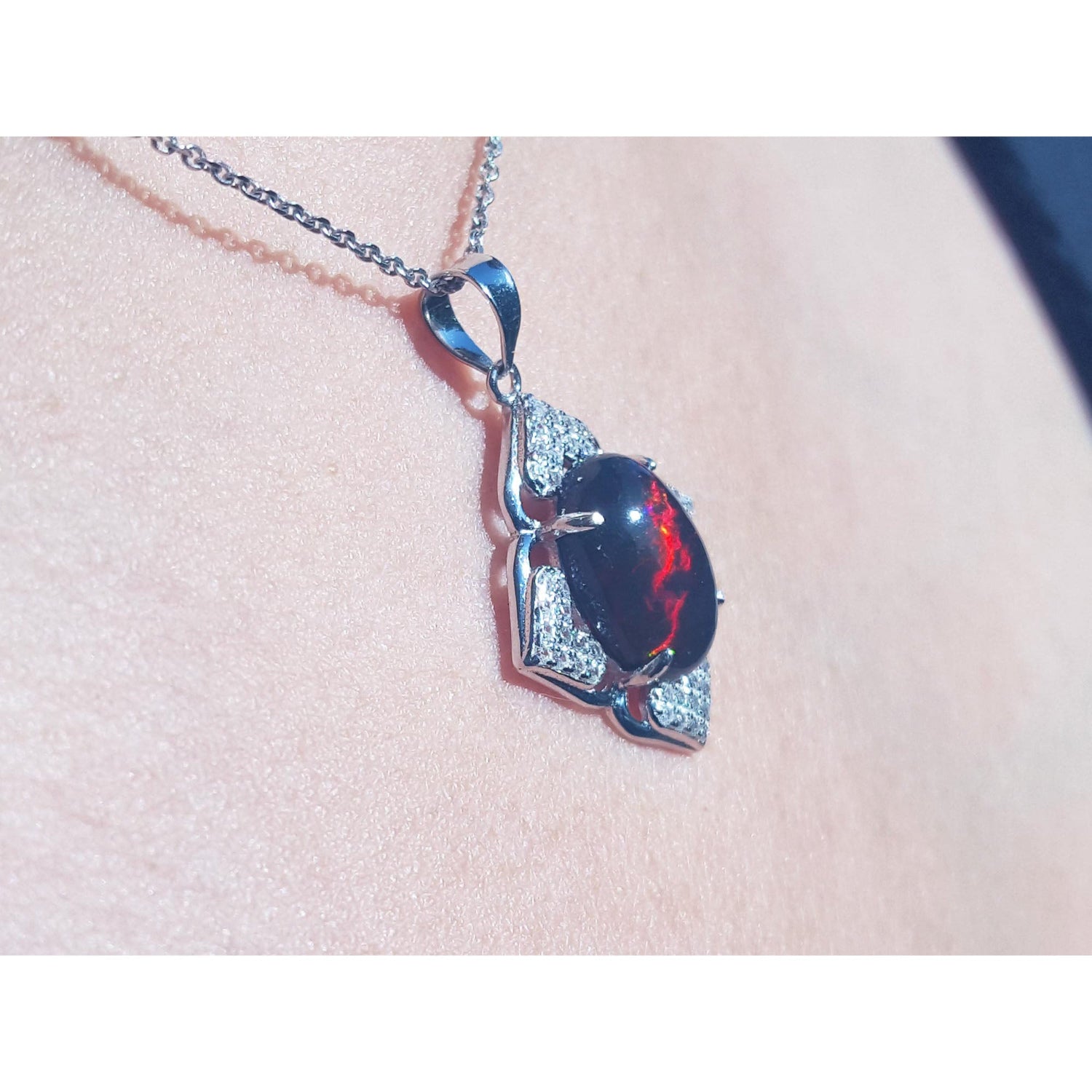 Silver pendant with a black opal pendant on a person&#39;s nek.