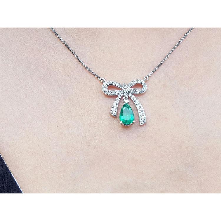 18K white gold bow-tie necklace with pear-shaped emerald and diamonds on a chain.