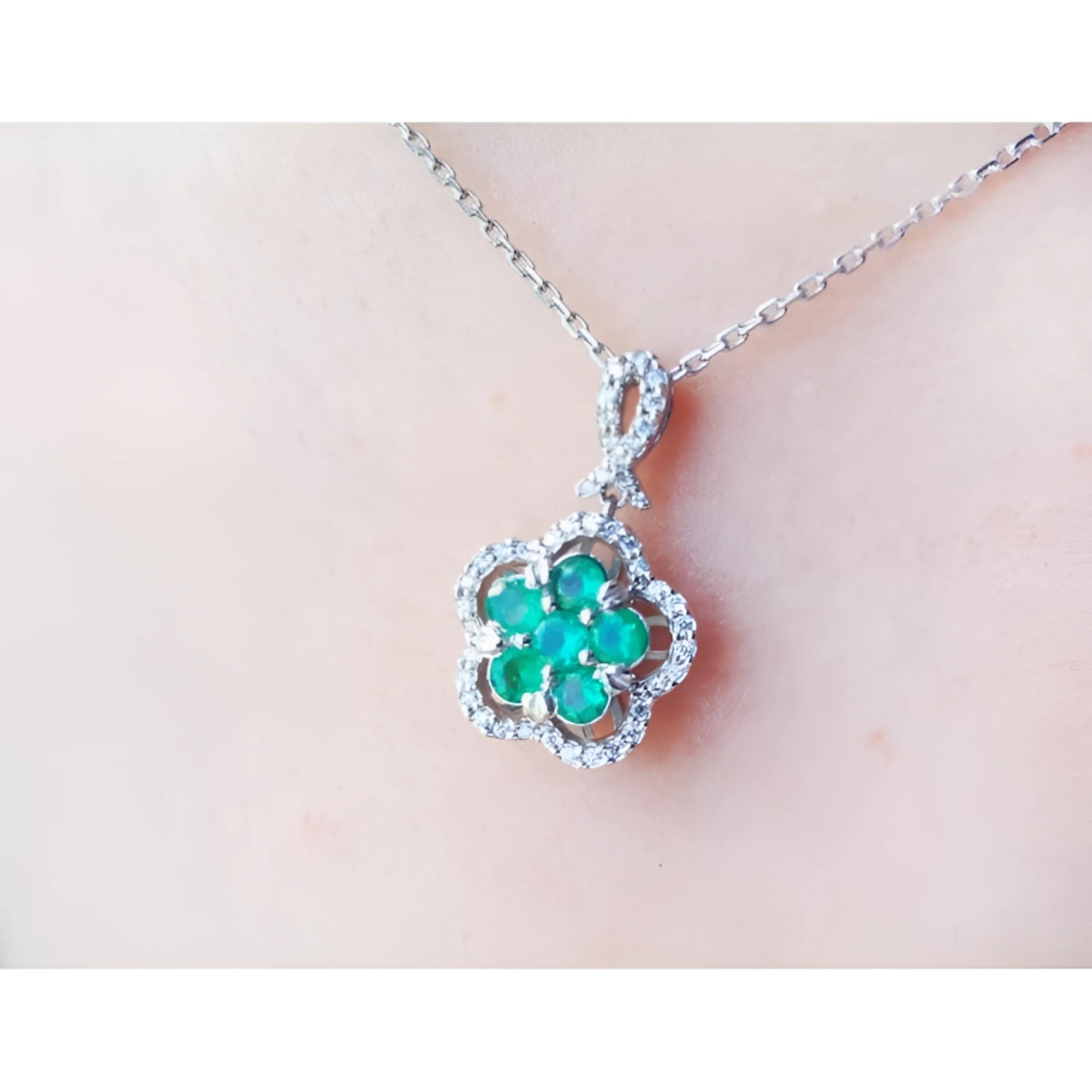 14K white gold emerald cluster necklace with diamond halo, clover-like five-petal design.