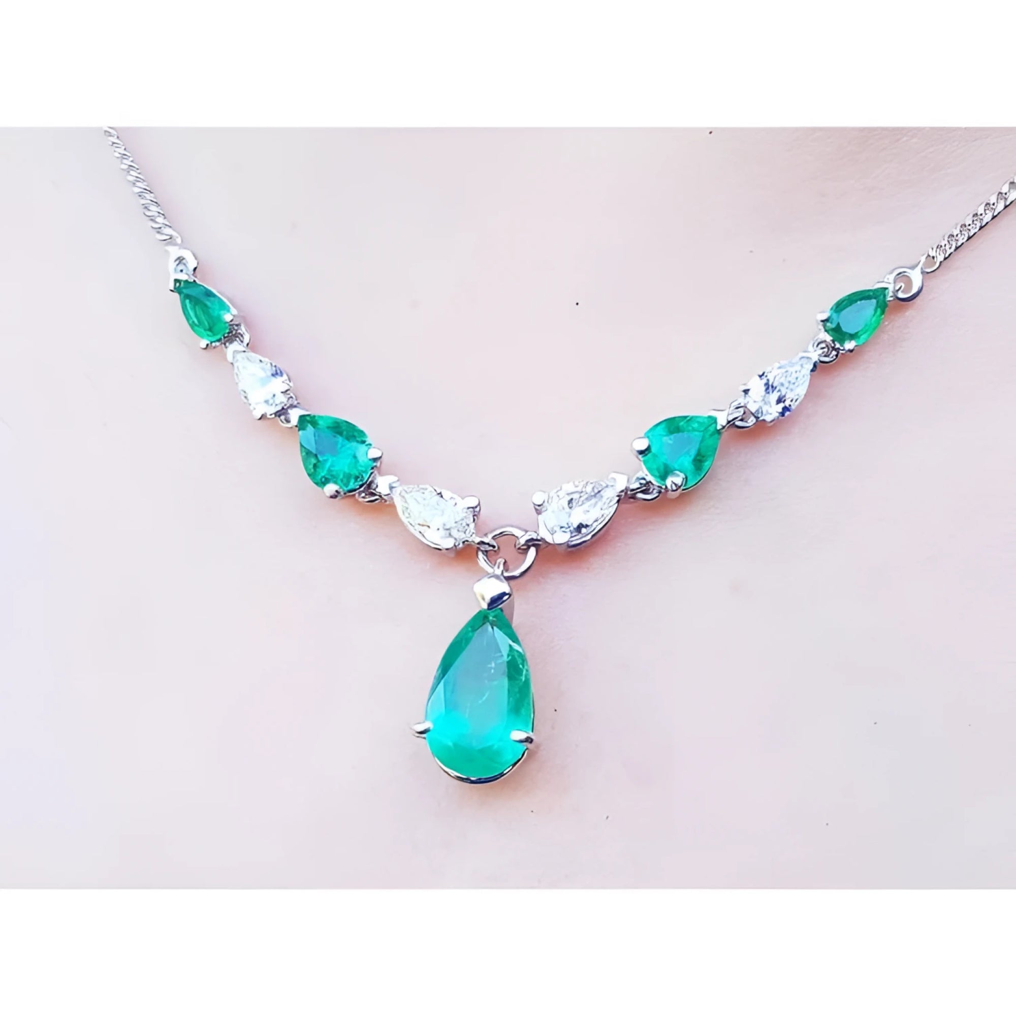 14k white gold necklace with pear-shaped emeralds and diamonds, featuring a large emerald drop pendant.