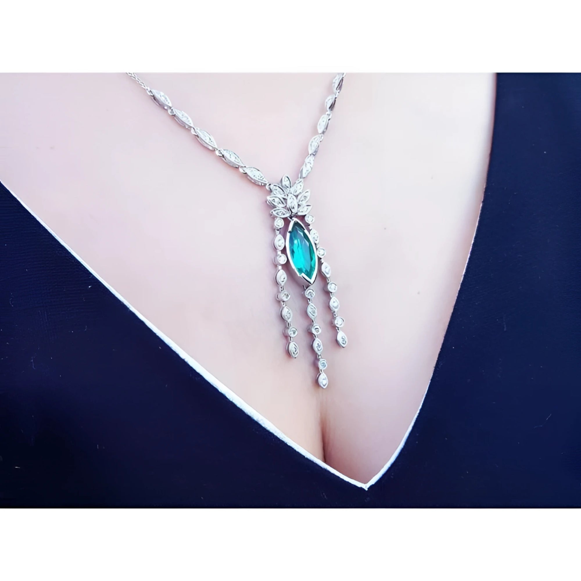 Marquise cut Colombian emerald necklace in 14K white gold with diamond links, worn on a woman's chest.