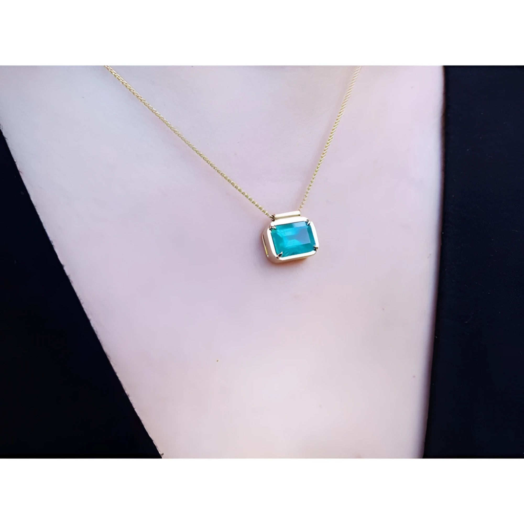 Natural Muzo Colombian emerald solitaire necklace in 18K yellow gold, east-west orientation.