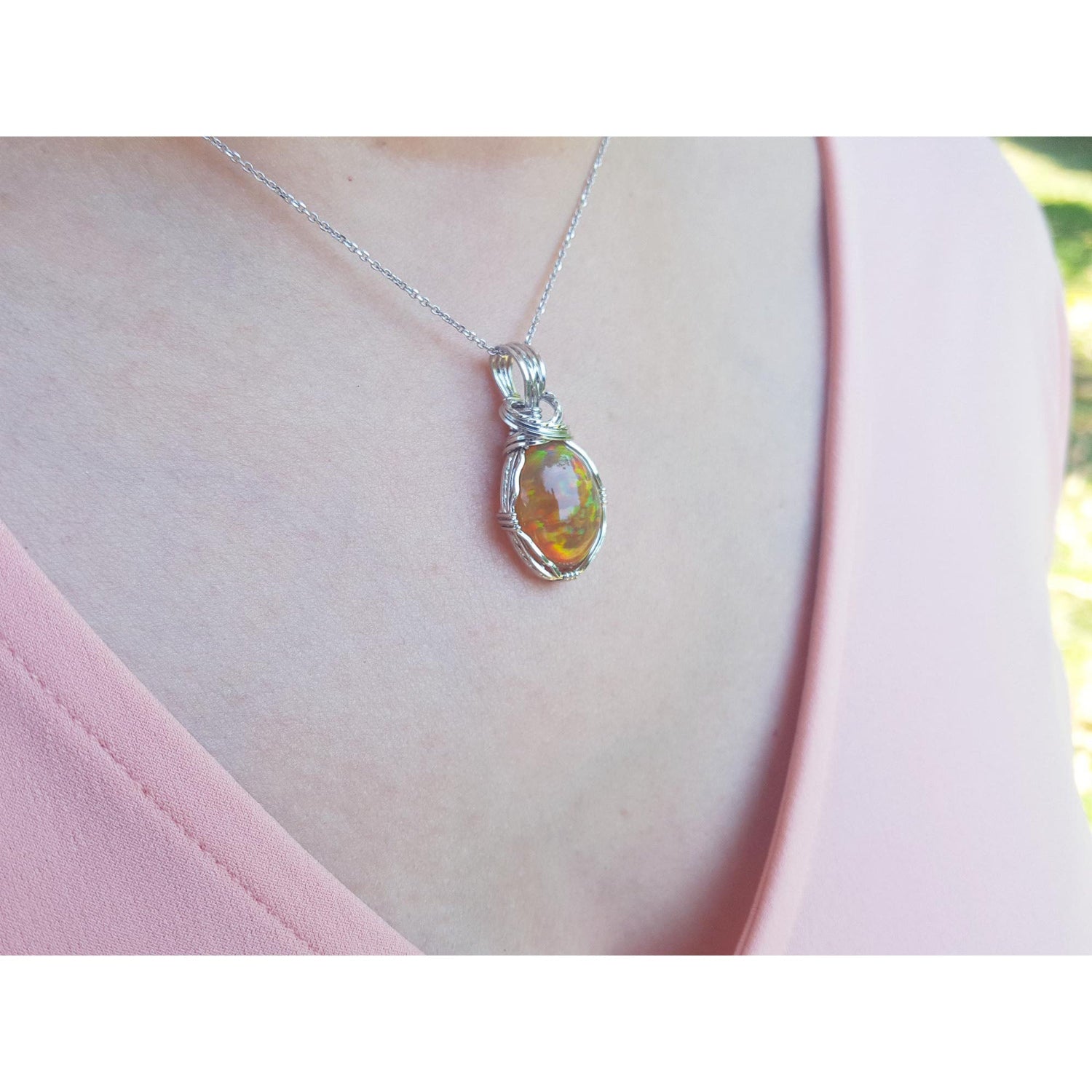 Opal pendant necklace on a person&#39;s neck wearing a pink top.